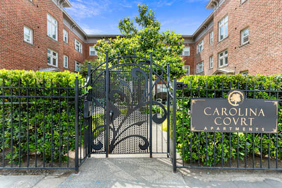 The entrance to the Carolina Court apartments is gated and surrounded by greenery.