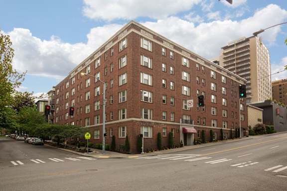 A large red brick building with a flat roof and a yellow sign on the side.