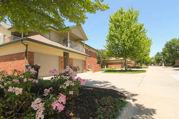 a sidewalk in front of a building with trees and flowers