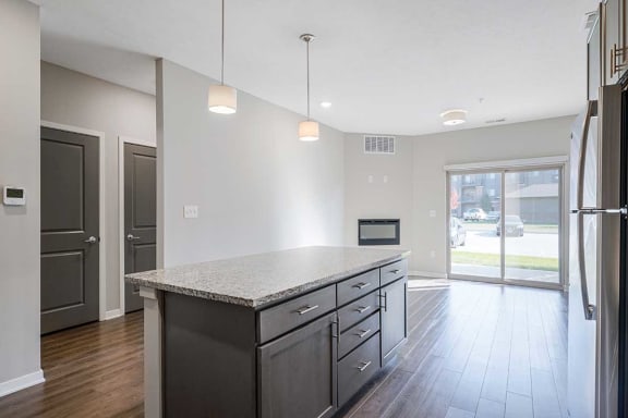 a kitchen with an island next to an open living room and a doorway to the hall