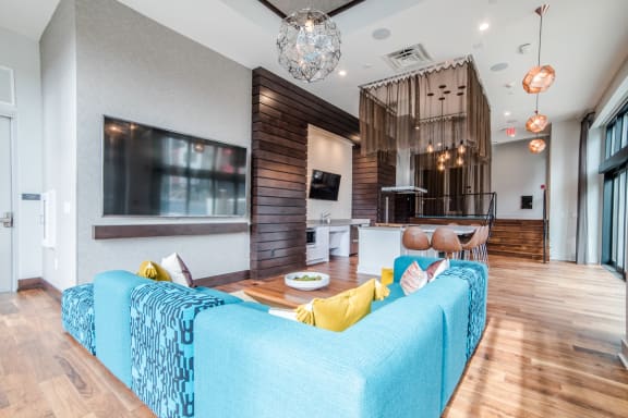 Indoor lounge area with TV, display kitchen, bar seating, theater seating and connected to outdoor pool at CityWay Apartments, Indianapolis, IN, 46204