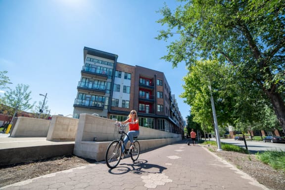 a woman riding a bike in front of a building at CityWay Apartments, Indianapolis, IN, 46204