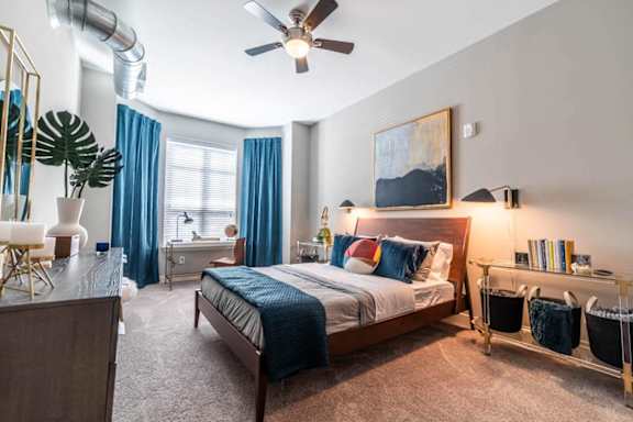 A bedroom with a bed, a ceiling fan, and a desk with a chair at The Foundry Apartments , South Bend, IN, 46617