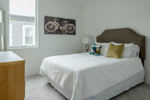 a bedroom with a bed and a painting of a bike on the wall