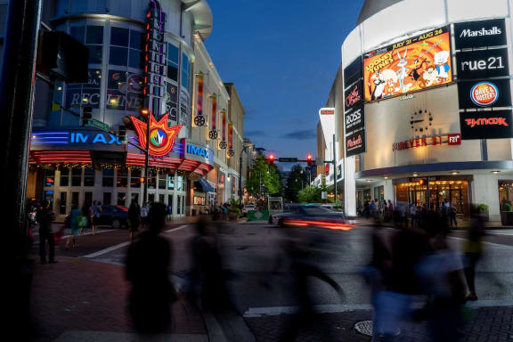 people crossing the street in front of a movie theater at night