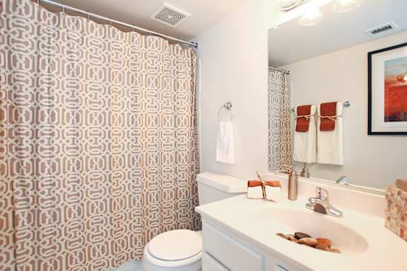 A bathroom with a toilet, sink, and shower curtain. at Copper and Quarry Village, Pikesville, 21209