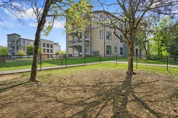 a yard with two trees in front of an apartment building at Radius on Grove, Austin, TX, 78741