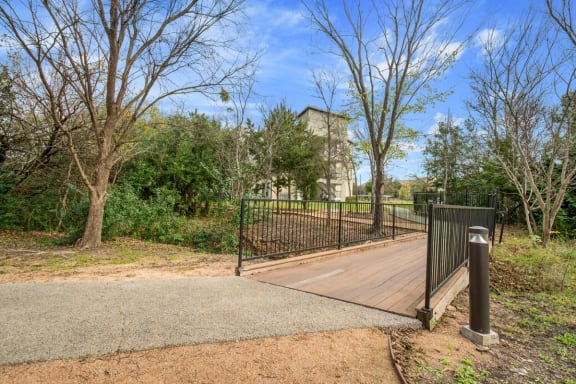 the park has a bridge with a fence and a building in the background at Radius on Grove, Austin, TX, 78741