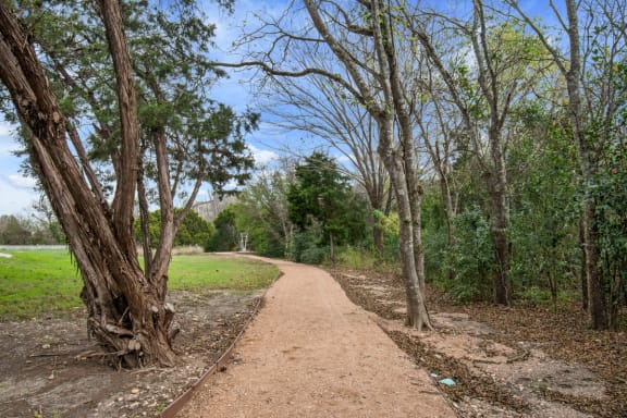 a dirt trail with trees on both sides of it at Radius on Grove, Austin, 78741