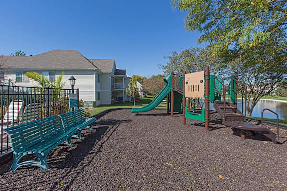 A playground with a green slide and benches.