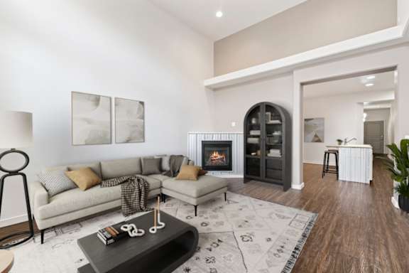 A living room with a fireplace and a kitchen in the background.