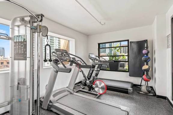 A treadmill in a room with a window overlooking a cityscape.