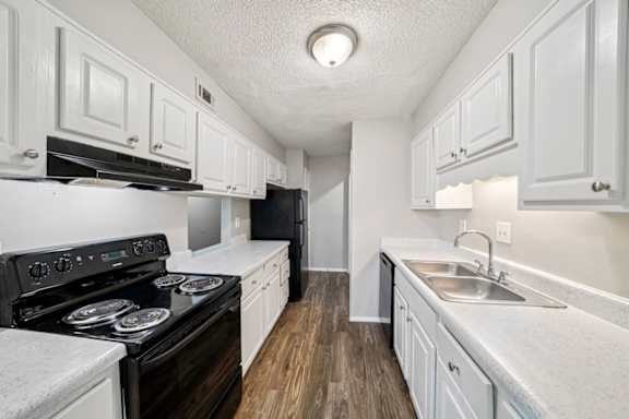 A kitchen with white cabinets and a black stove top oven.