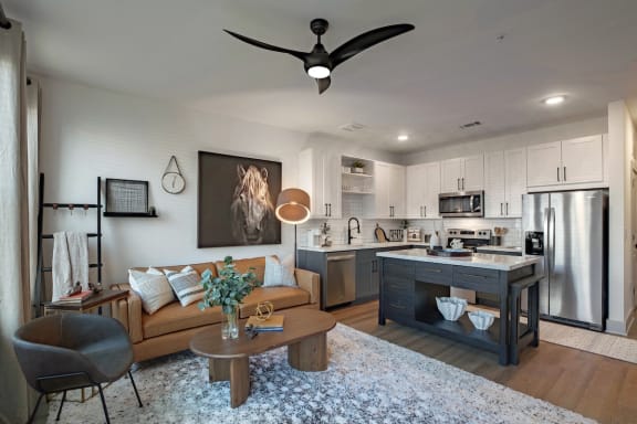 a living room with a kitchen and a ceiling fan