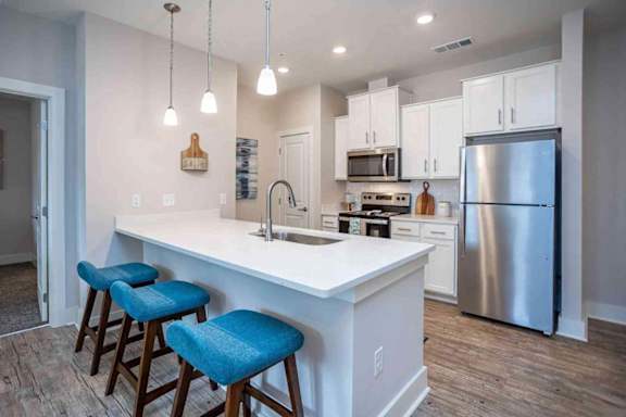 A kitchen with a white counter and blue stools.
