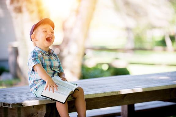 child_laughing_holding_book at Sumida Gardens Apartments, California