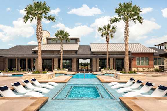 Beautiful swimming pool surrounded by palm trees, elegant landscaping, and thoughtfully designed gathering areas.