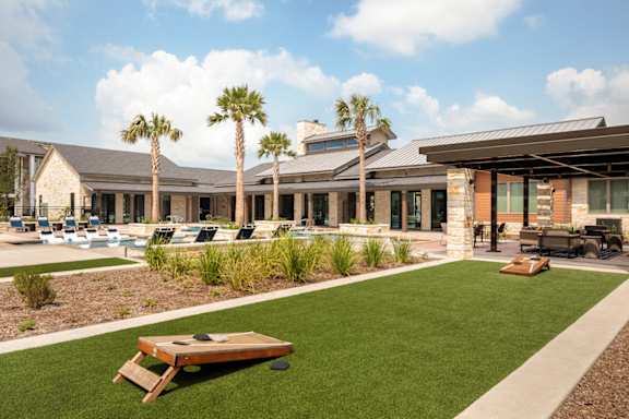 Upscale outdoor amenity area with a resort-style pool, covered lounge pavilion, and lawn games for residents to enjoy.
