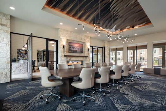 Sophisticated resident clubhouse featuring a large conference table, modern fireplace, and designer finishes throughout.