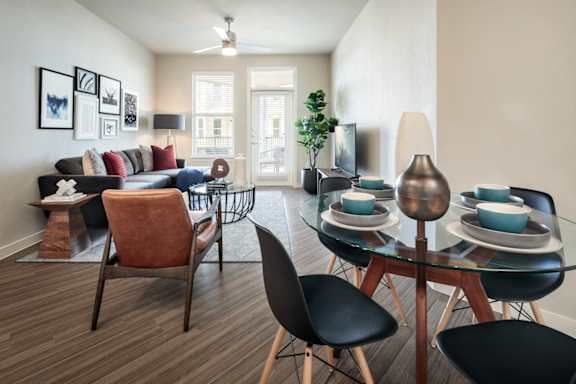 Bright open-concept living and dining area with contemporary furnishings, large windows, and access to a private balcony.