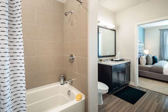 Modern bathroom featuring a spacious vanity, granite-style countertops, and a sleek tub-shower combination.