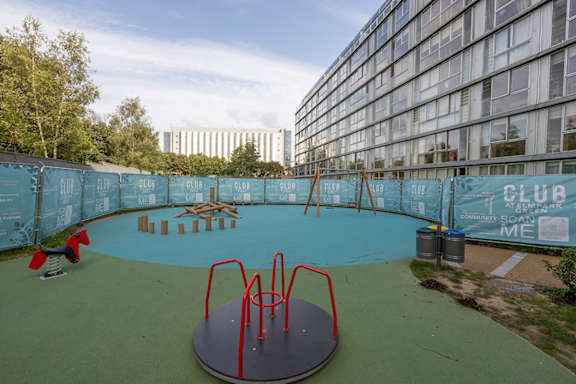 a playground at an apartment building with a swimming pool