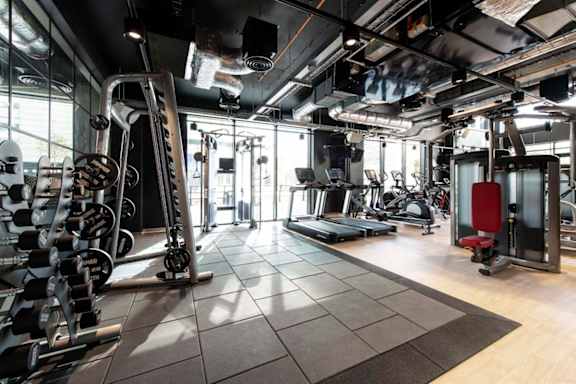 A gym with a variety of equipment including weights and cardio machines.