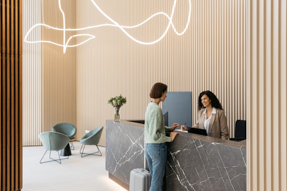 two women standing at the front desk of a hotel lobby