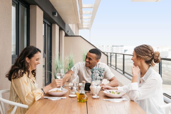 three people sitting at a table eating food and drinking wine