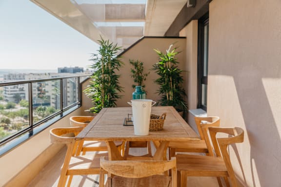 a dining table and chairs on a balcony with a city view