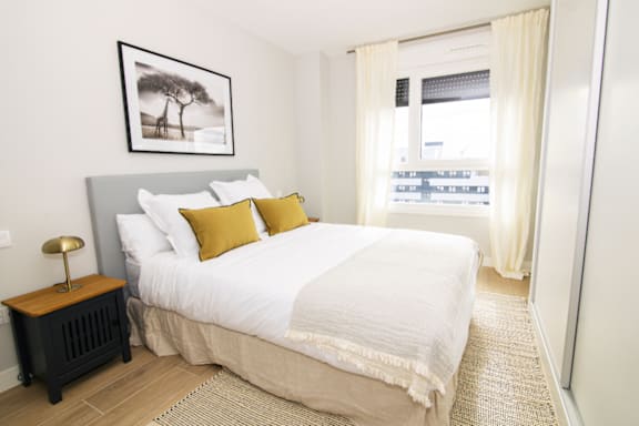a bedroom with a large white bed and a window