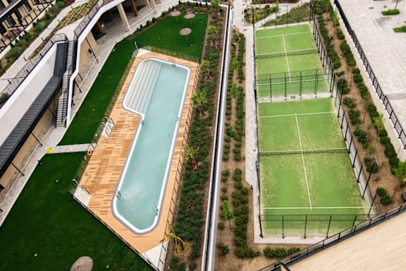 a pool with a wooden deck next to a tennis court