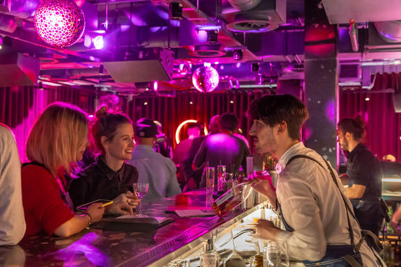a group of people sitting at a bar with drinks