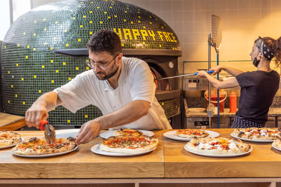 a man and a woman preparing pizzas in a pizzeria