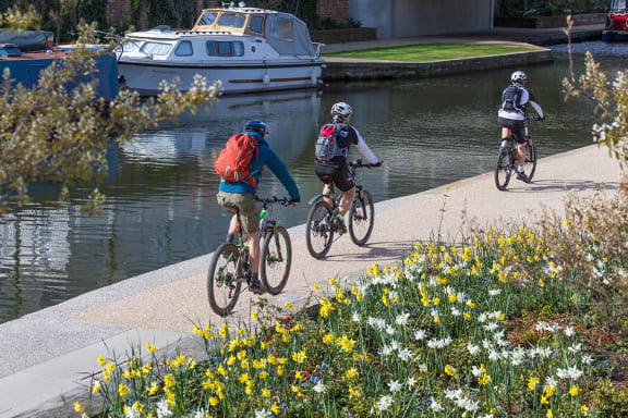 a group of people riding bikes on a path next to a river