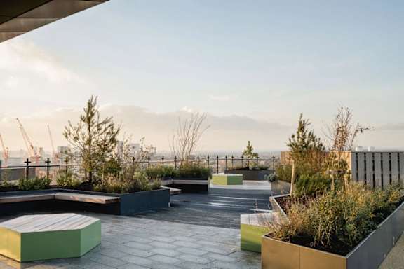 the roof terrace at dusk with benches and plants at Vox Apartments, Manchester, M15 4YD