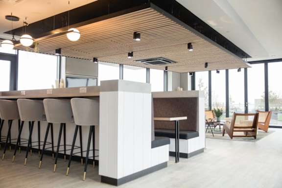 a bar with chairs and a table in a room with windows at Vox Apartments, Manchester, M15 4YD