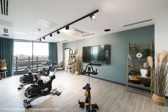 a gym with exercise bikes and a tv on the wall at Vox Apartments, Manchester, M15 4YD