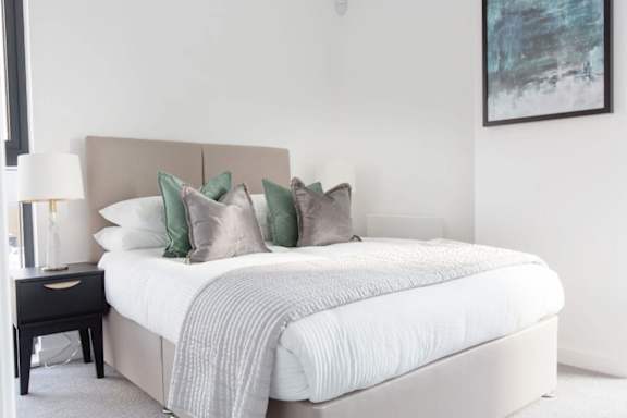 a bedroom with a large bed with white sheets and pillows at Vox Apartments, Manchester
