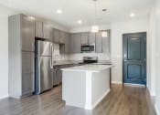 Thumbnail 3 of 8 - an open kitchen with stainless steel appliances, grey cabinets, and granite counter tops