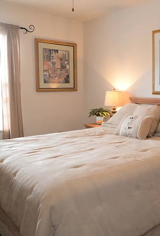 A bedroom with a large bed and two lamps.