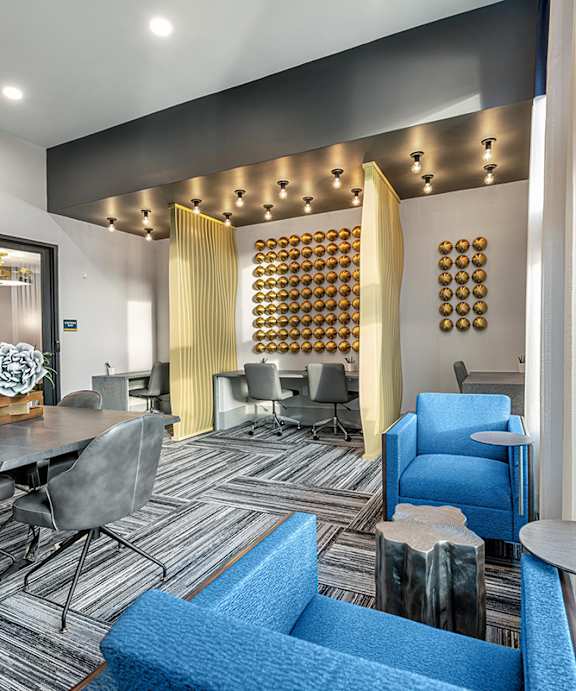 A modern living room with a grey table and blue chairs.