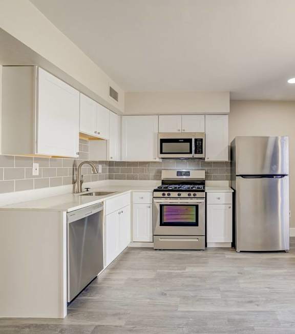 A kitchen with a refrigerator, oven, and microwave.