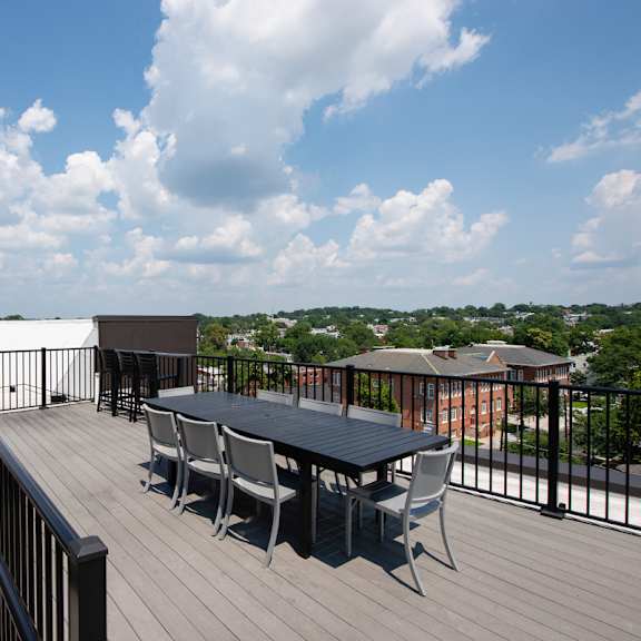 A balcony with a table and chairs overlooking a cityscape.