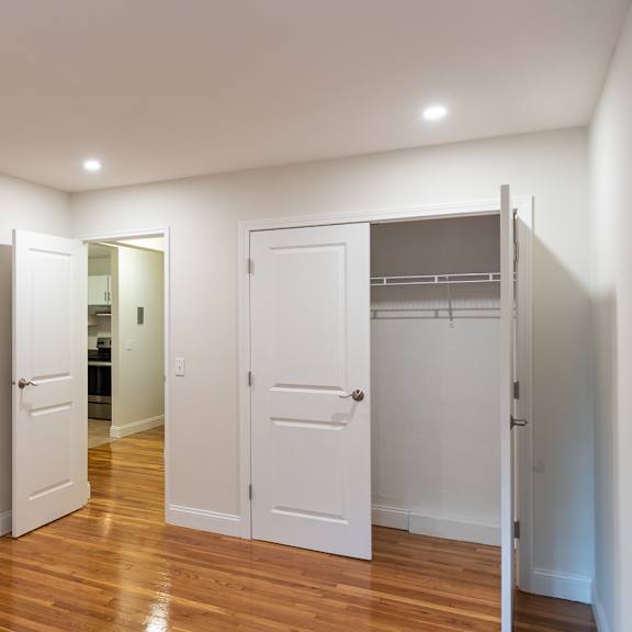 A modern kitchen with stainless steel appliances and wooden chairs.