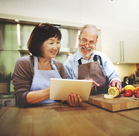 a man and woman in a kitchen looking at a tablet