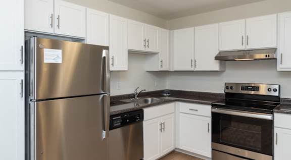 A modern kitchen with a stainless steel refrigerator and a wooden stool.