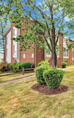 a grassy area with trees in front of a brick building