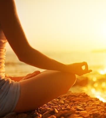 Lifestyle photo of woman at the beach meditating 
