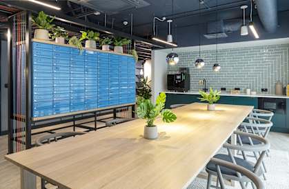 a large wooden table in a room with blue tiles and chairs